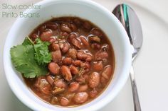 a white bowl filled with beans and cilantro on top of a white plate