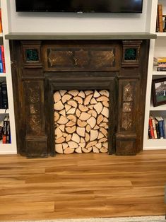 a fire place with logs stacked in front of it and a flat screen tv mounted on the wall