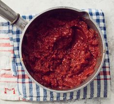 a pot filled with red sauce on top of a blue and white towel