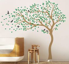 a tree with green leaves and birds painted on the branches is in front of a white wall