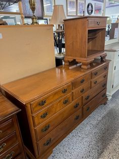 an old dresser with a large open box on it's top, and other furniture in the background