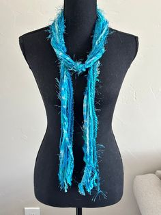 "This handmade scarf consists of a variety of yarns in turquoise. Each of my scarves and no two are ever the same.  Each scarf is made up of a selection of Sari Silk, Eyelash, Ribbon, Ladder, Fuzzy, Sparkly, Pouf Pom Pom, Boucle, Flag Ribbon, Nub, Pluscious, Hand Spun, and Brushbound.  It is approximately 72\" long. This is an open fringe style, secured in three places along the scarf, allowing for styling flexibility, and can be worn as an accent belt.  It is a light weight scarf. Check out this YouTube link https://www.youtube.com/watch?v=5LYAEz777AU for a demonstration of the many ways that you can style this scarf." Bohemian Blue Scarves For The Beach, Blue Bohemian Scarves For Beach, Bohemian Blue Scarves For Beach, Blue Silk Scarf As Gift, Blue Festival Scarf, Handmade Blue Shawl For The Beach, Blue Handmade Beach Shawl, Blue Bohemian Silk Scarf For Beach, Bohemian Blue Silk Scarf For Beach