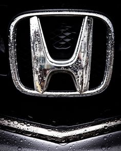 the front end of a honda car with water droplets on it's grills