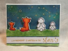 a handmade card with three cartoon animals on the grass and stars in the sky