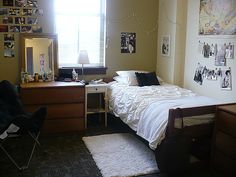 a small bedroom with a bed, desk and dresser in the corner next to a window