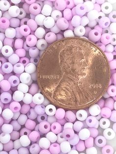 a penny sitting on top of a pile of pink and white beads