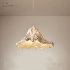 a lamp hanging from a ceiling in a room with a mountain on the wall behind it