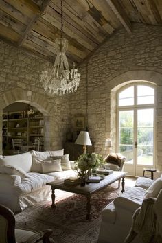 a living room filled with lots of furniture and a chandelier hanging from the ceiling