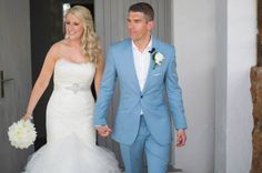 the bride and groom are walking down the steps together in their wedding attire, holding hands