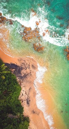 an aerial view of the ocean and beach with waves crashing on it's shore