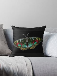 a colorful butterfly sitting on top of a black couch throw pillow with the image of a green, red and yellow butterfly