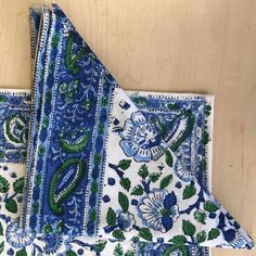 two blue and green paisley napkins sitting on top of a wooden table