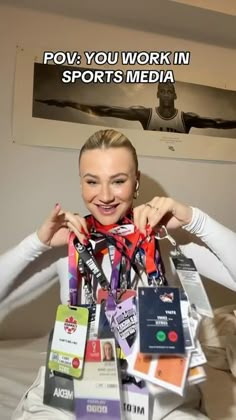 a woman sitting on top of a bed covered in lots of sports medals and ribbons