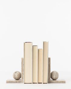 three books are stacked on top of each other in front of two rocks and one ball