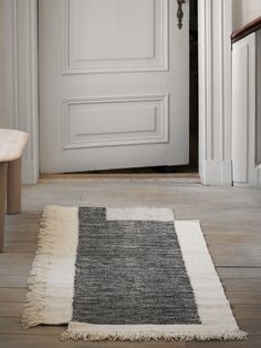 a white door with a black and grey rug on the floor