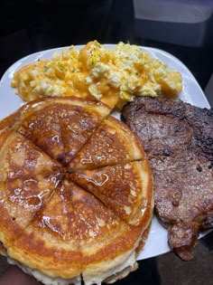 pancakes, scrambled eggs and bacon on a white plate