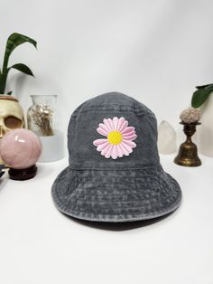 Welcome to Sarah's Little Cottage! This flower bucket hat is made with a 100% cotton bucket hat and a flower patch. The patch sits in the center and the hat is light gray. The patch is showcasing a beautiful daisy that is light pink with a yellow center. Measurements: 23.125 inches ( 58.74 cm) around the inside, and the inner band has an adjustable tie to make it tighter. Brim is 2.5 inches (6.35 cm) in length. Didn't find what you were looking for? Click here to see the rest of the shop! https://www.etsy.com/shop/sarahslittlecottage Fun Black Bucket Hat For Spring, Fun Cotton Bucket Hat, Fun Spring Bucket Hat With Curved Brim, Fun Cotton Hats For Spring, Vintage Cotton Bucket Hat, Retro Cotton Sun Hat With Curved Brim, Retro Spring Bucket Hat With Curved Brim, Retro Cotton Brimmed Bucket Hat, Retro Brimmed Cotton Bucket Hat