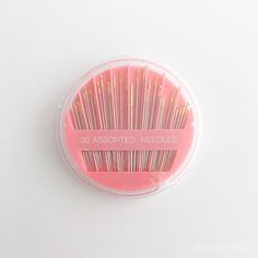 a pink and gold colored toothbrush in a plastic container on a white surface with the words 30 assorted needles