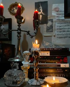 candles are lit on a table next to books