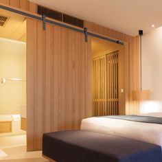 a bed sitting in a bedroom next to a wooden wall and sliding glass closet doors