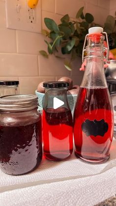 three jars filled with liquid sitting on top of a counter