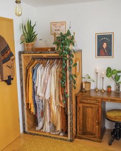 a closet with clothes hanging on it and a potted plant in the corner