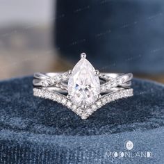 a white gold ring with a pear shaped diamond on top and two rows of diamonds around the band