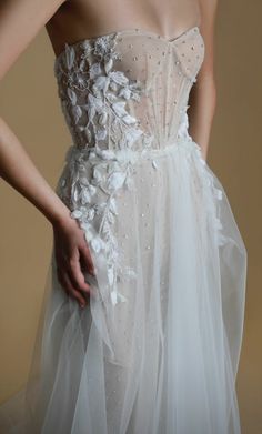 a woman in a white wedding dress with flowers on the waist and tulle skirt