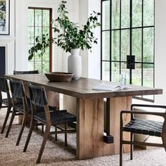 a dining room table with chairs and a potted plant in the center, next to a fire place