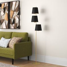 a living room with a green couch and three lamps on the wall next to it