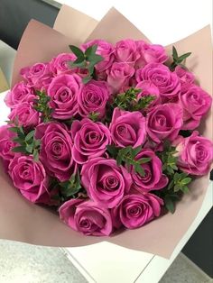 a bouquet of pink roses is sitting on the counter top, ready to be delivered