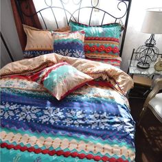 a bed with colorful comforters and pillows on it