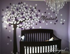 a baby's room decorated in purple and white with a tree painted on the wall