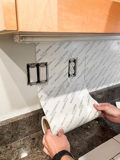 a person is wrapping up a roll of toilet paper on the kitchen counter with two rolls of toilet paper