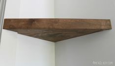 a wooden shelf sitting on top of a white wall