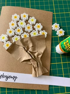 a piece of brown paper with white and yellow flowers on it next to glue bottle