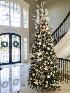 a decorated christmas tree in the middle of a foyer