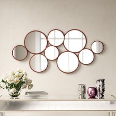 a white table topped with a vase filled with flowers and lots of mirrors on the wall