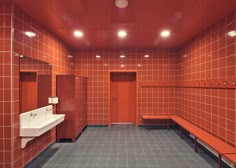 a public bathroom with red tiles and white sinks on either side of the stall doors