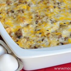 a casserole dish with eggs and cheese in it on a red tablecloth