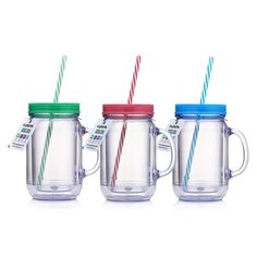 three glass mugs with colorful lids and two drinking straws in each one, on a white background