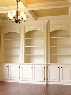 an empty room with built in bookcases and chandelier on the ceiling