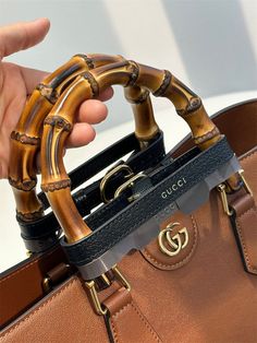 a person holding a brown gucci handbag with bamboo decorations on it's handles