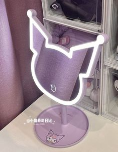 a purple cat shaped light up on top of a white table next to some shoes