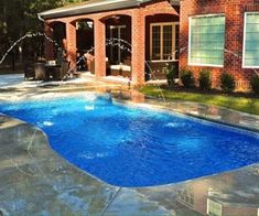 a backyard with a swimming pool and water sprinkles in the foreground