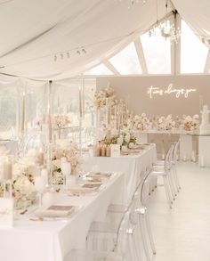 a long table is set up with white flowers and candles for an elegant wedding reception