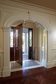 an open door leading into a hallway with wood flooring and white trim on the walls