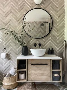 a white sink sitting under a round mirror next to a wooden cabinet with baskets on it