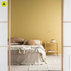 a bed sitting in a bedroom next to a wall with yellow paint on the walls