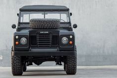 a black land rover parked in front of a concrete wall